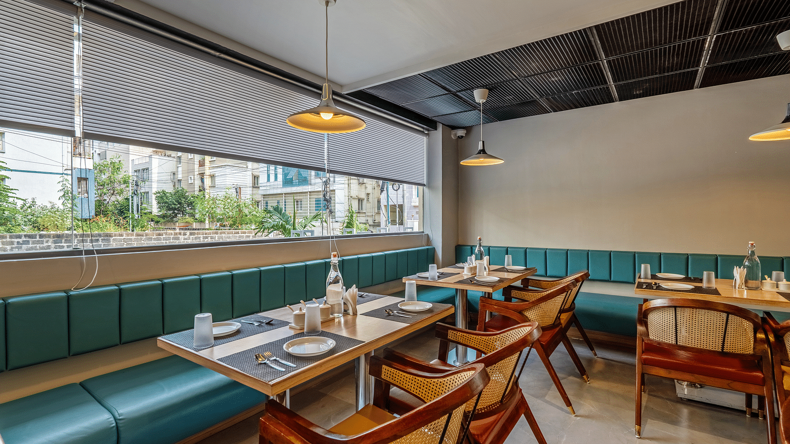 Image of a section of fine dining seating in the restaurant at the hotel with a table and a elegant head lamp |  Eminent Suites & Apartments, Hi-Tech City 