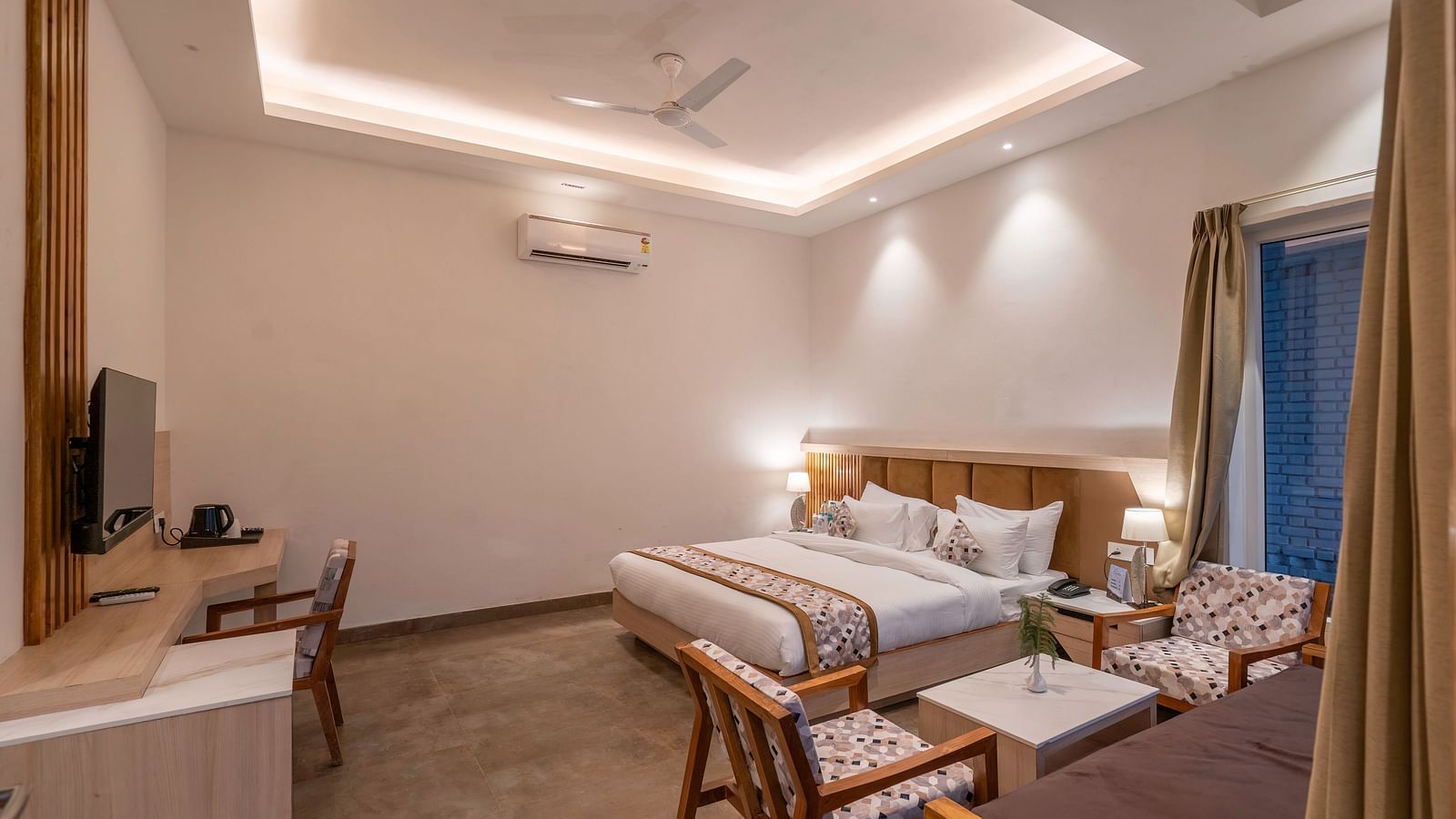A shot of the hotel room with a king-size bed, a seating area, and a work desk.