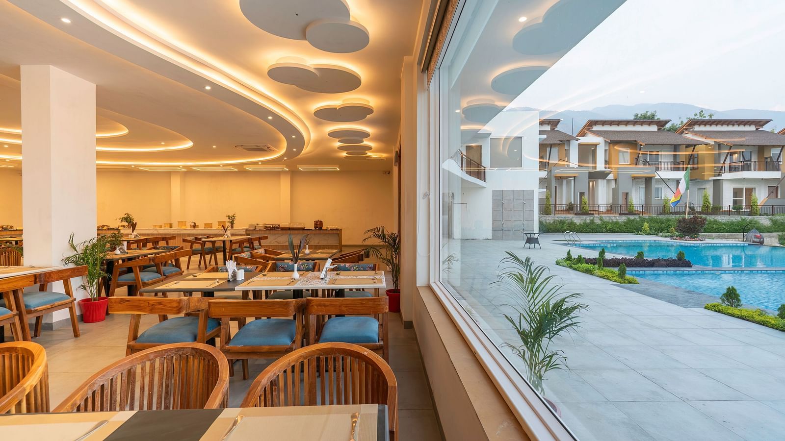A modern dining room with a view of the resort grounds through large windows.