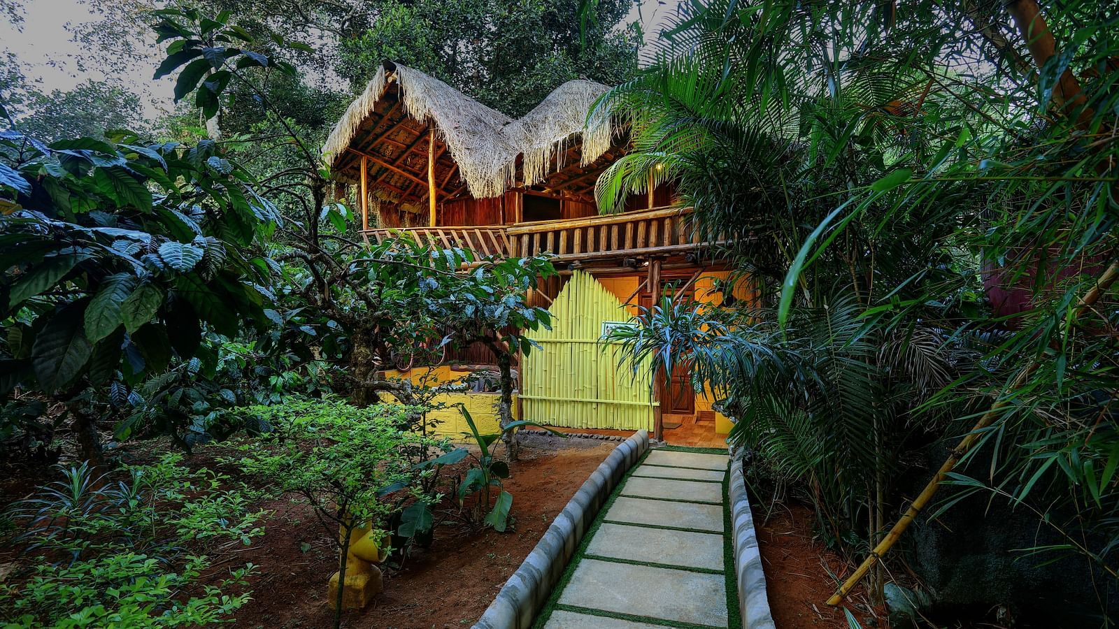 A facade image of the Family Wooden Cottage with a stone pathway leading to the cottage and covered in greenery - Evergreen County