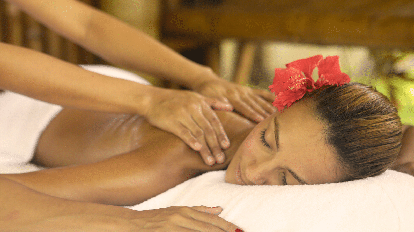 Spa therapist giving a relaxing massage to a woman with a flower in her hair at Flower Island Resort.