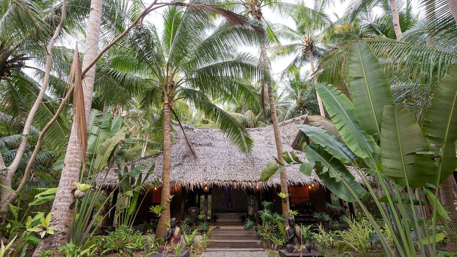 Flower Garden Resort entrance surrounded by palm trees and tropical greenery.