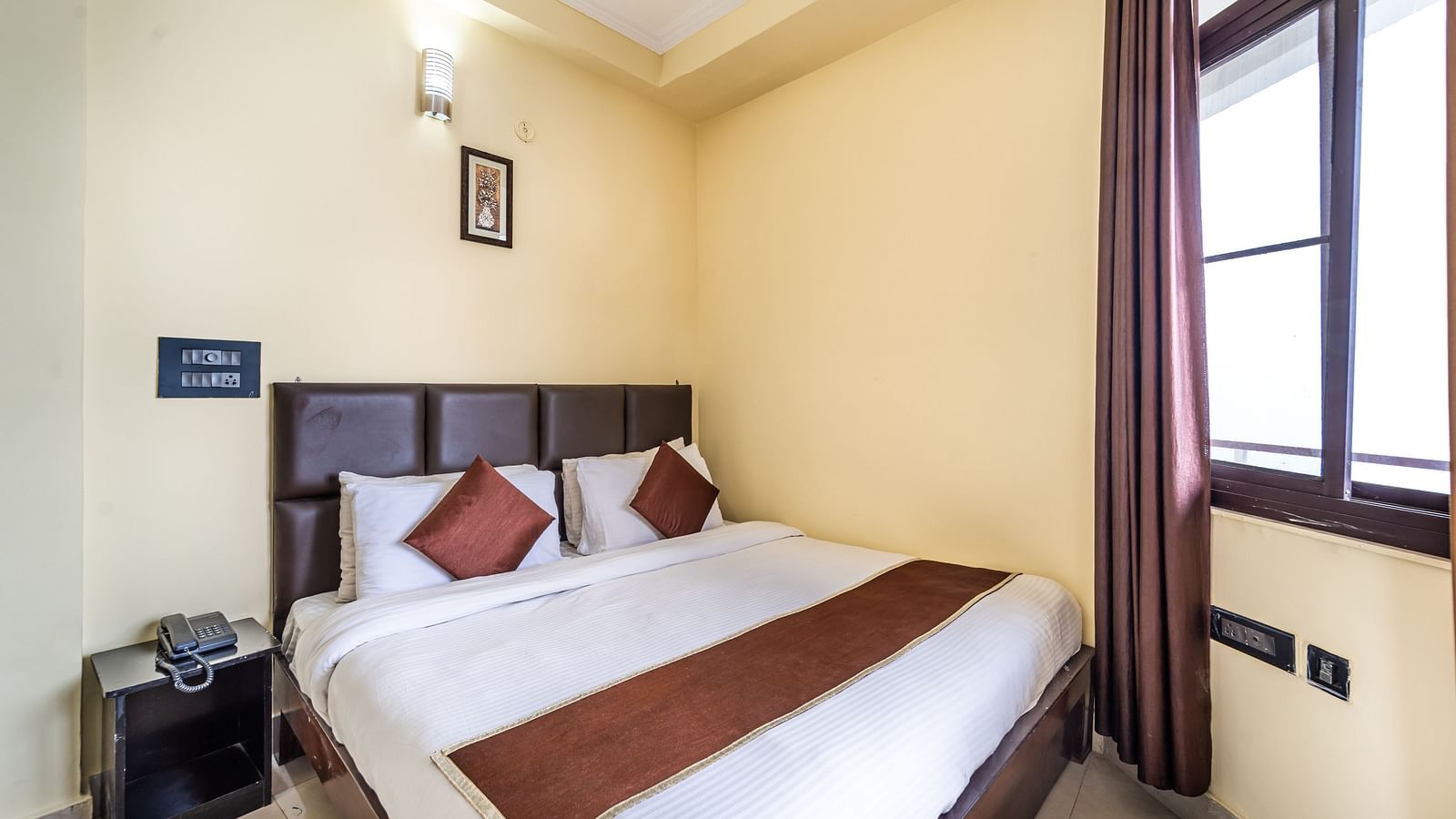 a room at Flutter Hotels & Resorts featuring a bed and a telephone placed on the side table