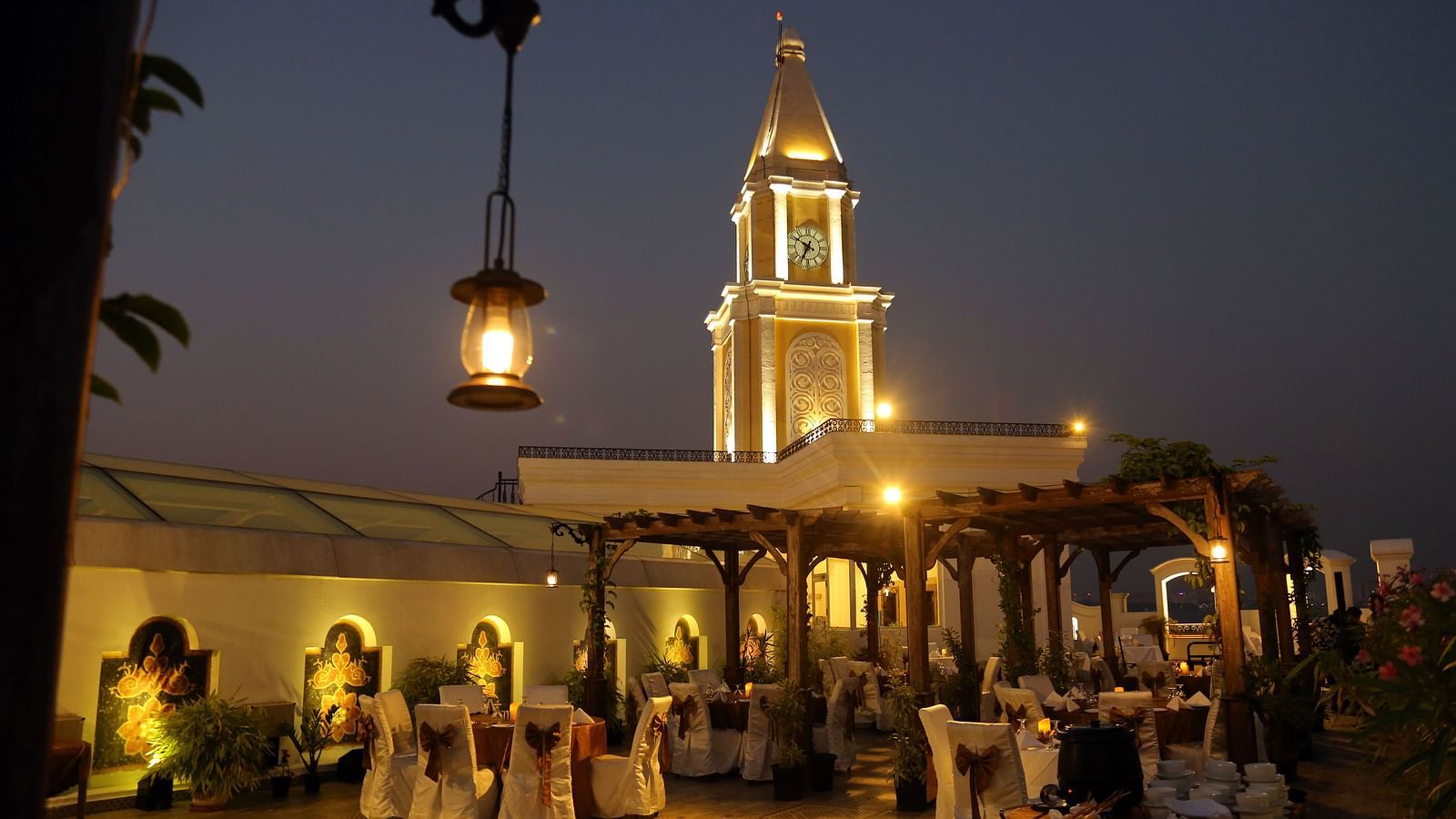 Rooftop clock tower at night, highlighted by decorative lighting against the night sky