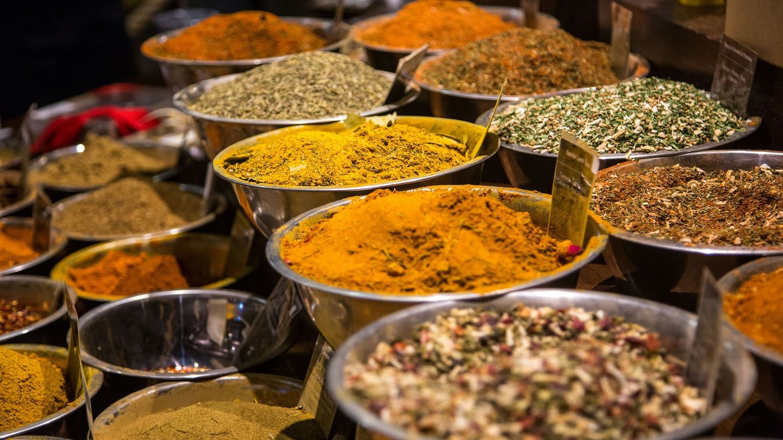 A series of bowls placed next to each other, each containing various spices