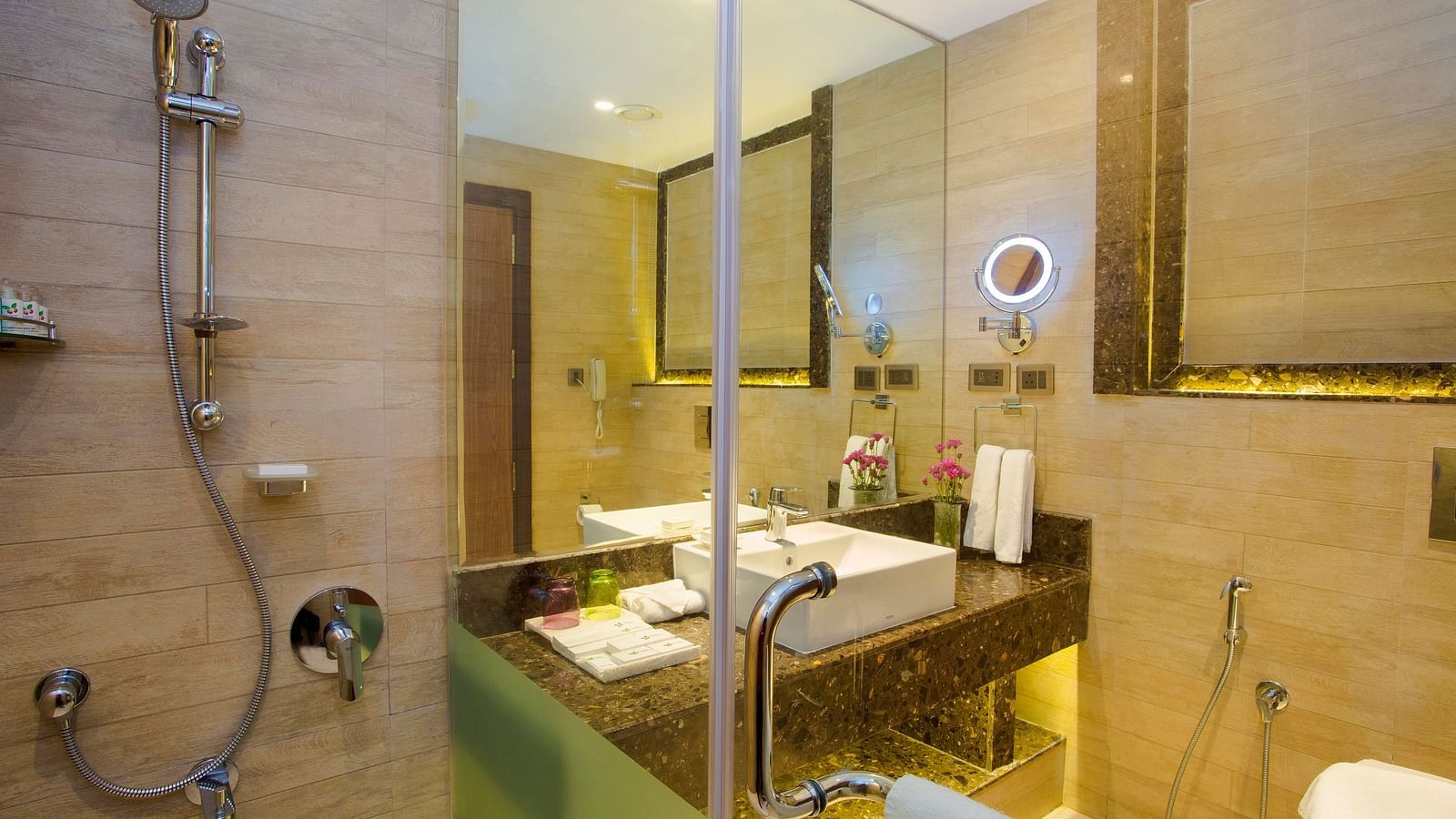 Bathroom with a mirror above the washbasin, separate lighting for it, and a glass partition separating the shower area.
