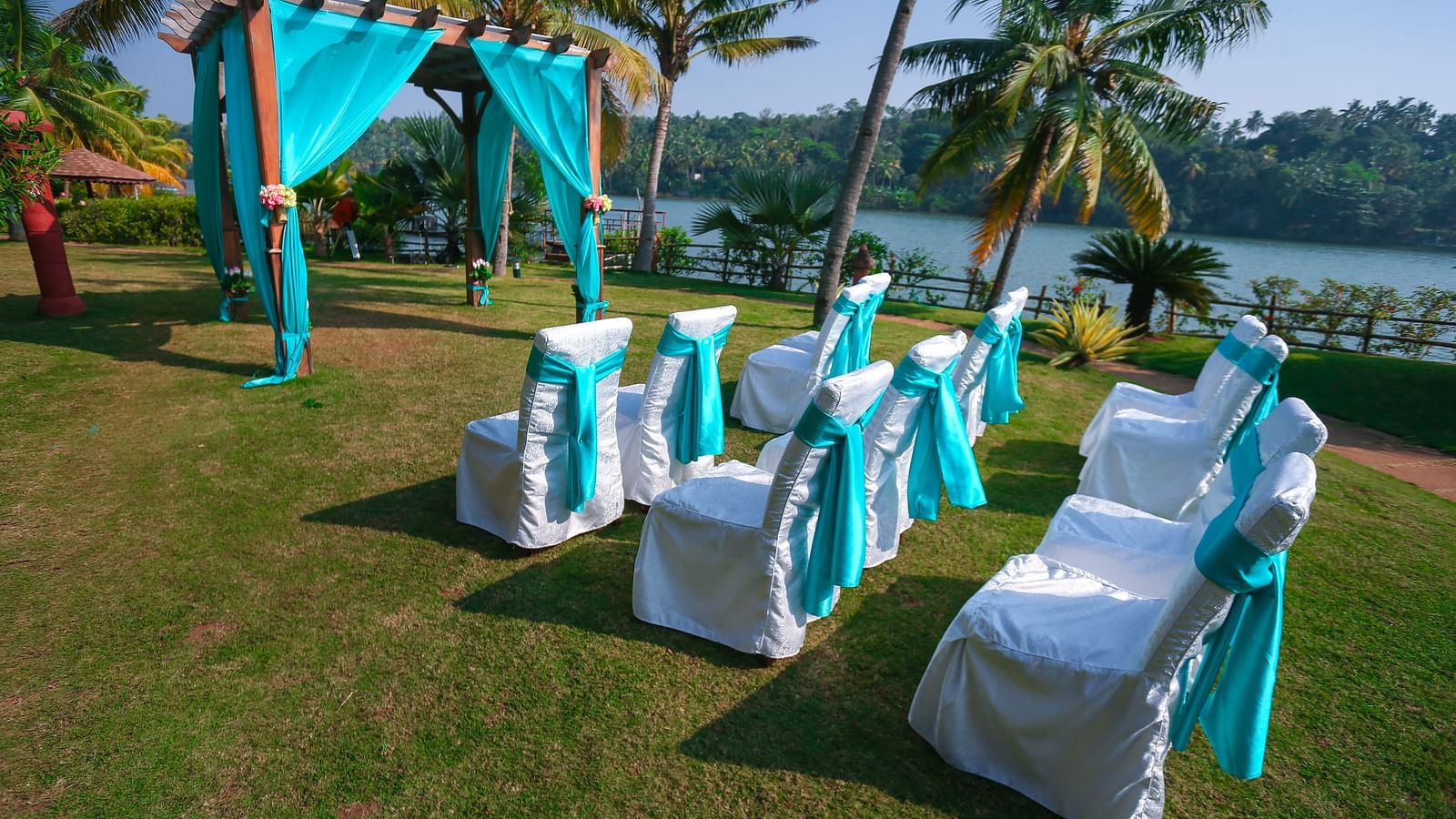 Chairs and decorations are arranged in the garden area for the wedding