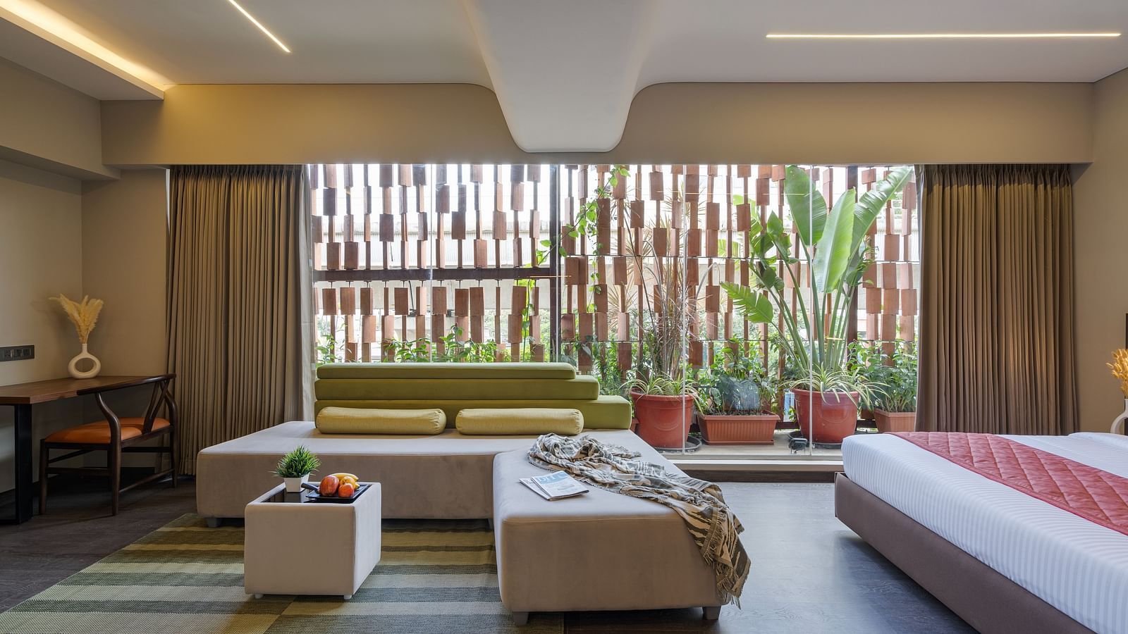 A white sofa with lime green pillows and a matching tea table kept in the center of the airy and bright room with floor to ceiling windows.