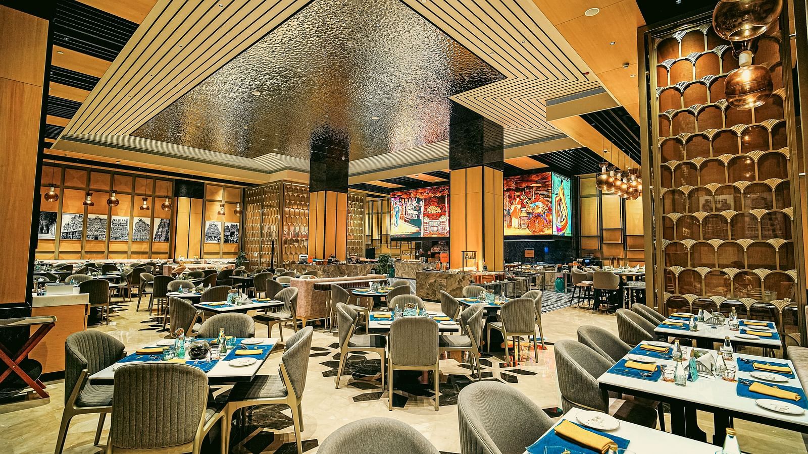 A wide view of the vibrant restaurant interior with elegant dining tables and unique ceiling design - Grand Madurai by GRT Hotels