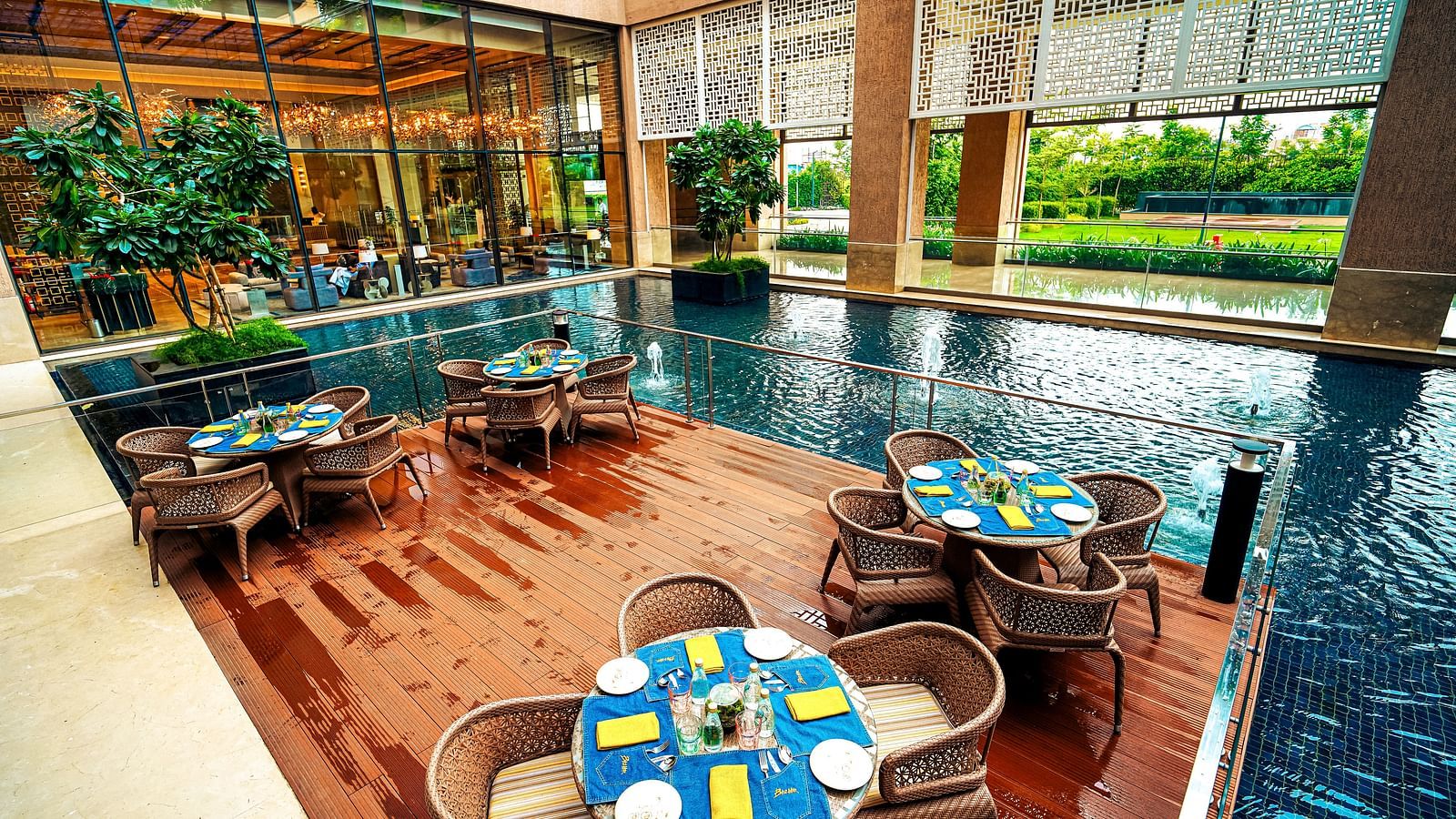 An alfresco dining space overlooking a reflective pool, surrounded by lush greenery - Grand Madurai by GRT Hotels