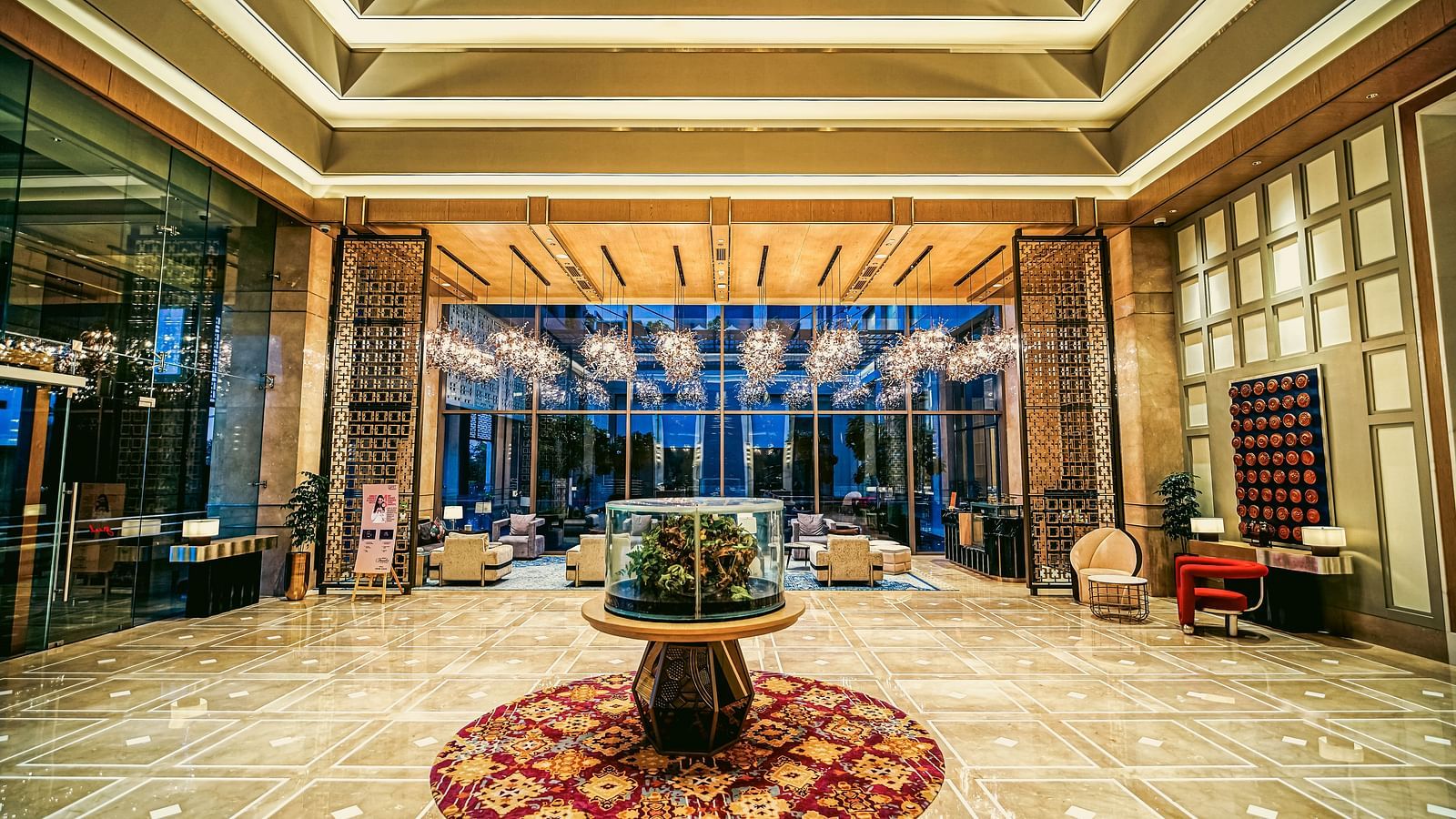A grand hotel entrance with expansive windows and elegant lighting, creating a luxurious atmosphere - Grand Madurai by GRT Hotels