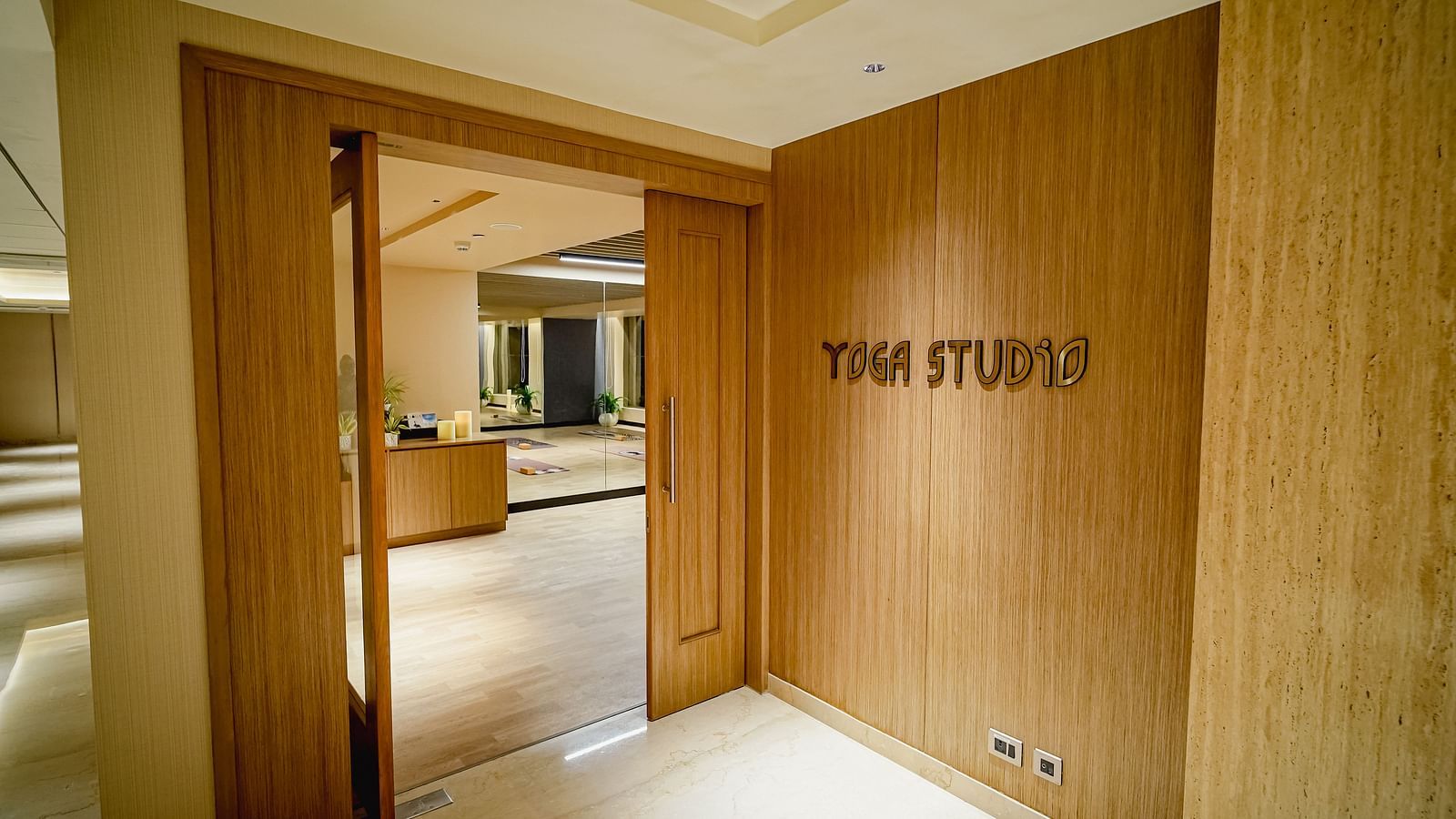  A brightly lit, minimalist yoga studio with large windows, wooden floors featuring a PVC folding door - Grand Madurai by GRT Hotels
