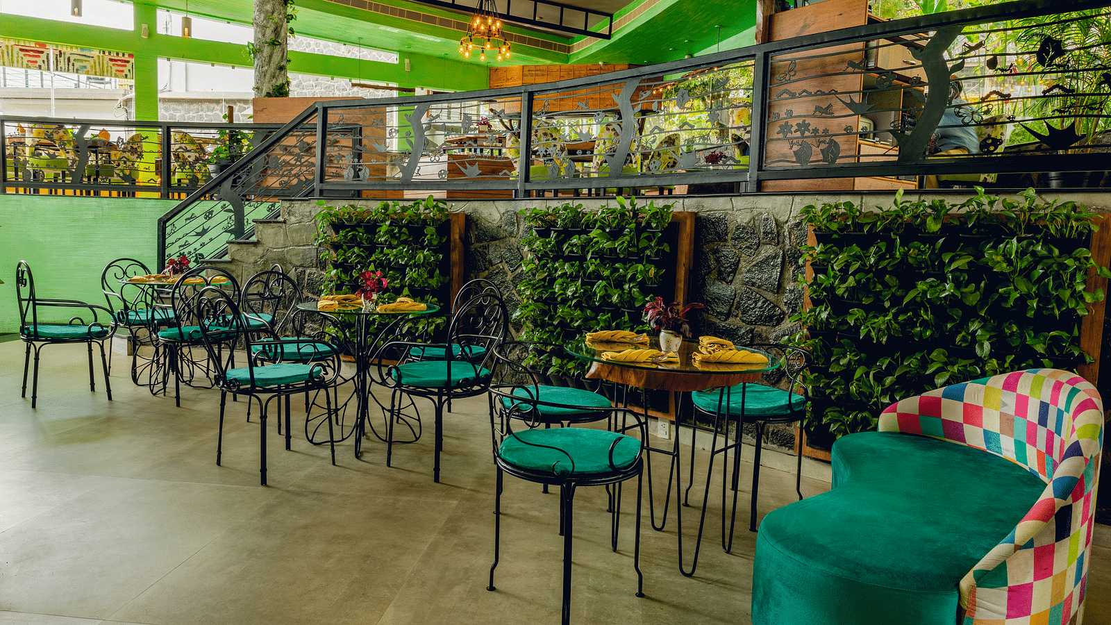 An image of a restaurant with two different areas for dining which are well decorated with plants and other items - An image of a restaurant with different seating arrangement and decorative items - Great Trails Yercaud by GRT Hotels
