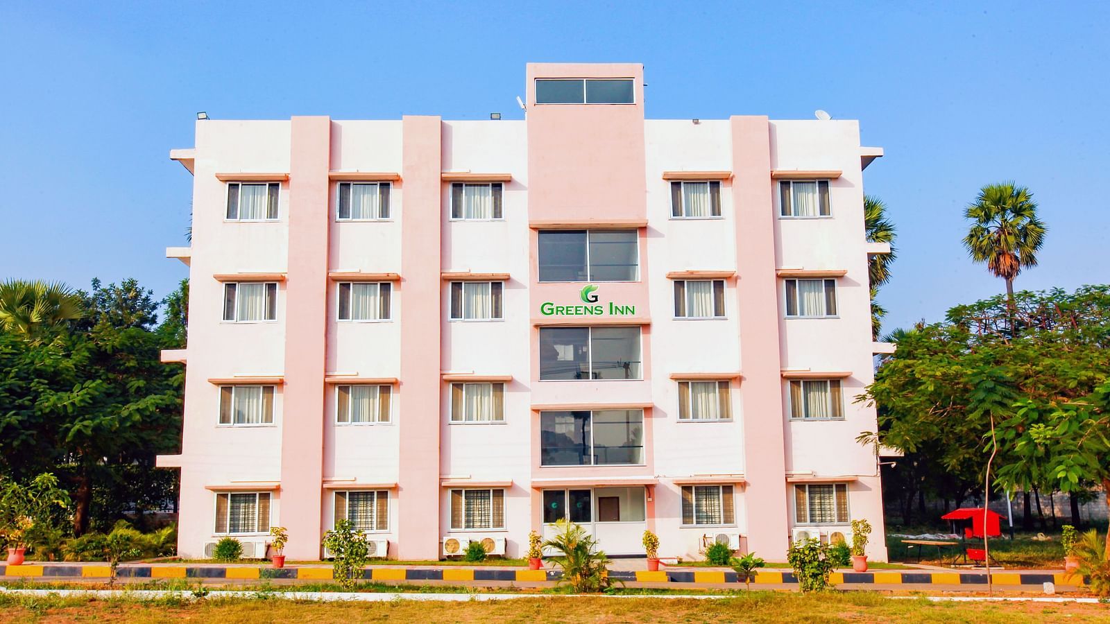 Facade of Greens Inn surrounded by trees during daytime - Tranquil Hotel in Hyderabad.