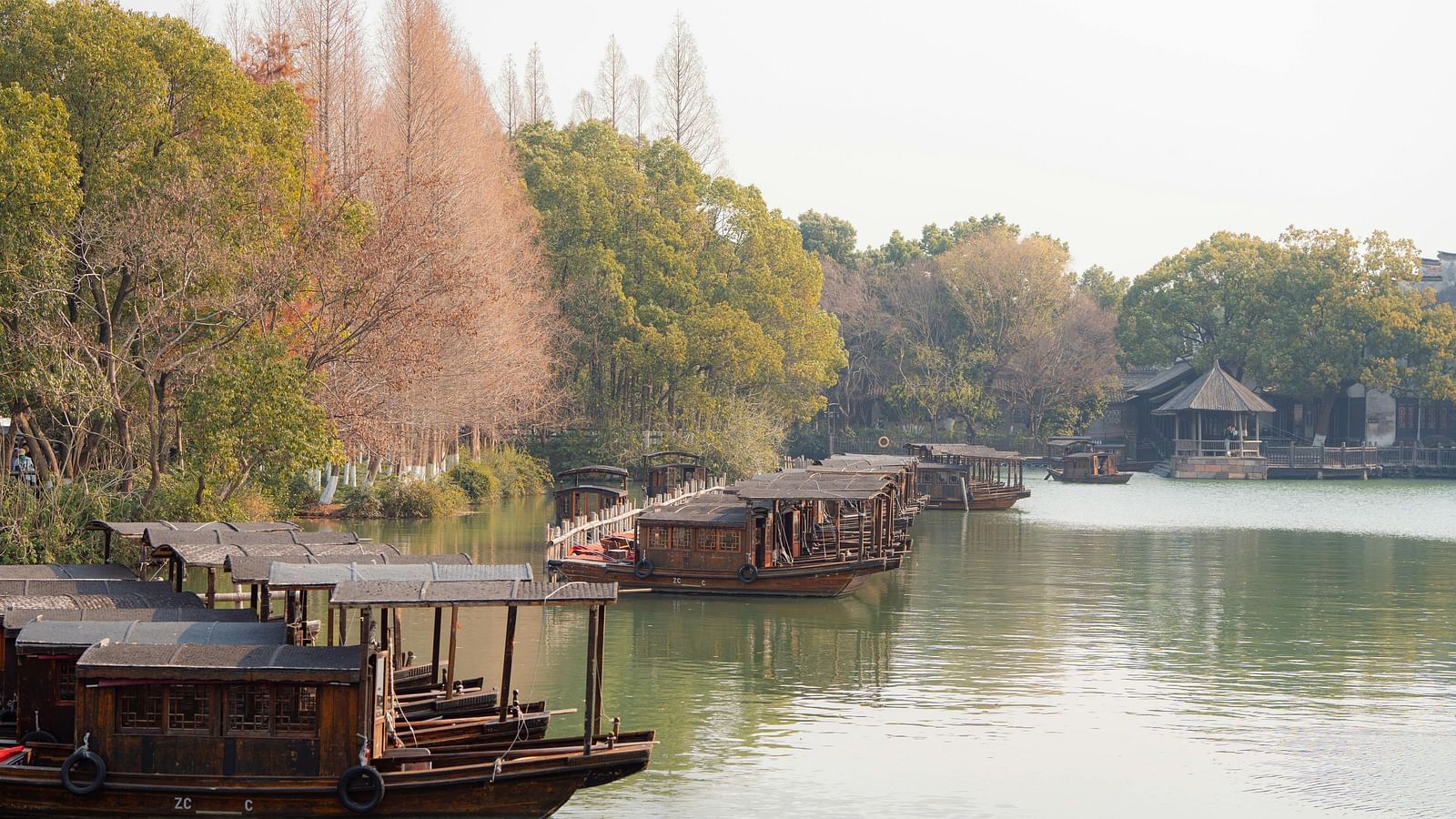 Serene riverside scene with boats and trees showcasing autumn colours.