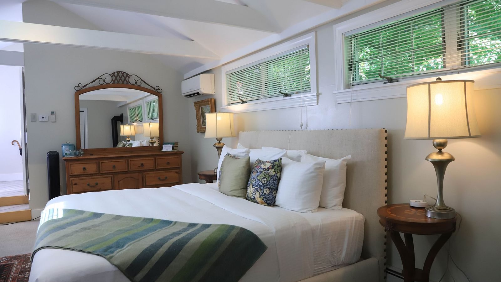 Hotel bedroom with green throw blanket and dresser at Hartstone Inn.