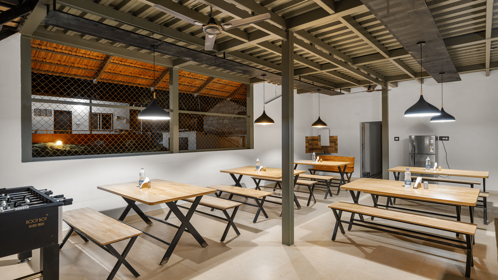 Dining area at Hatti Eden Coorg featuring spacious seating, wooden tables, modern lighting and a relaxed ambience, offering guests a comfortable space to enjoy freshly prepared meals.