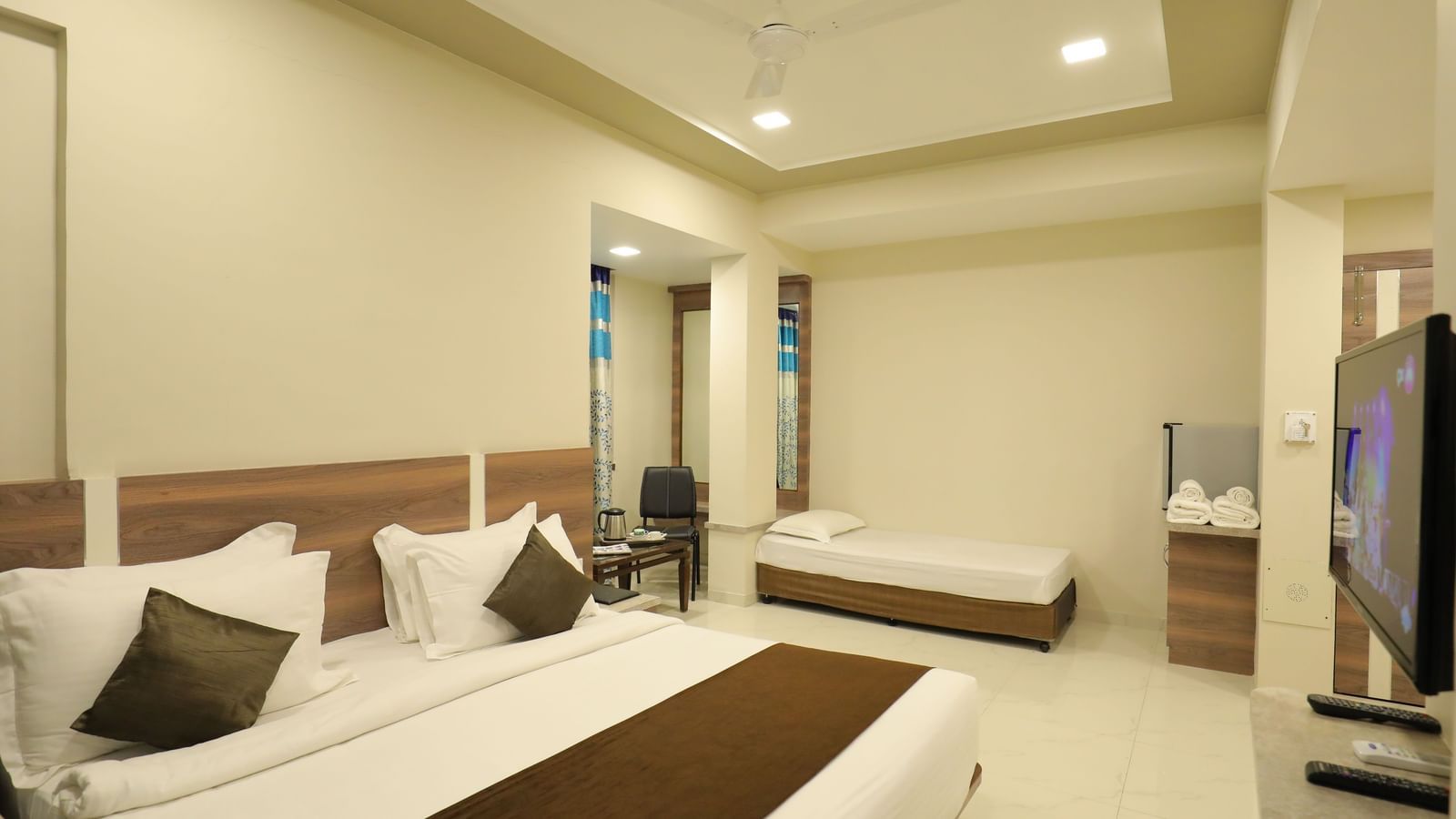 Close up of the king size bed and single bed in the Suite of Highland Resort, facing a wall-mounted TV.