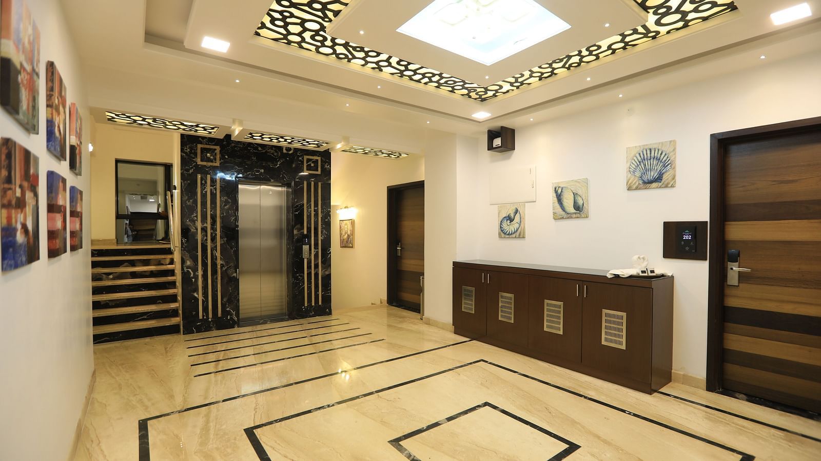 Image of a hall with a table on the side and lights on the ceiling at Hotel Altitude, Madikeri.