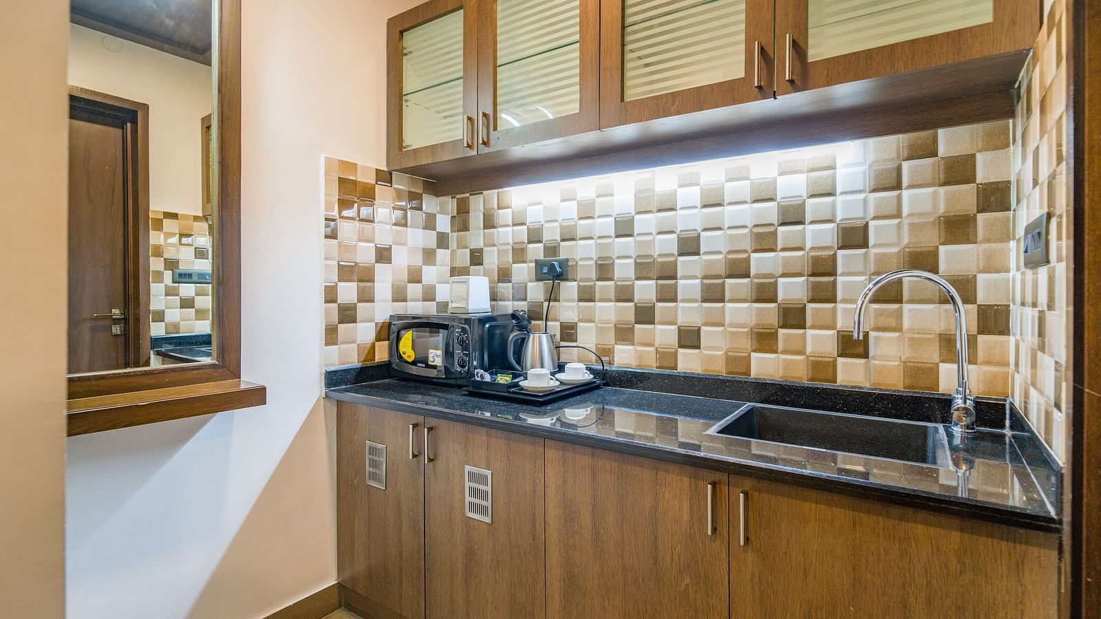 Image of a kitchen with a modern amenities and a sink on the side at Hotel Altitude, Madikeri.