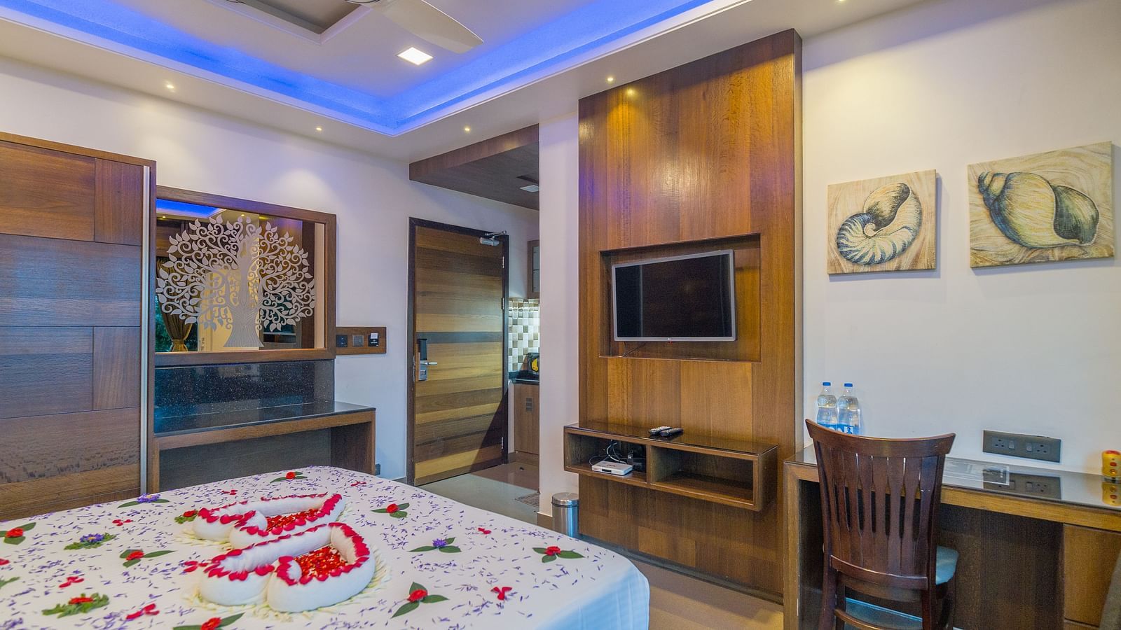 Image of a room with a bed decorated with flower petals and a television in front at Hotel Altitude, Madikeri.