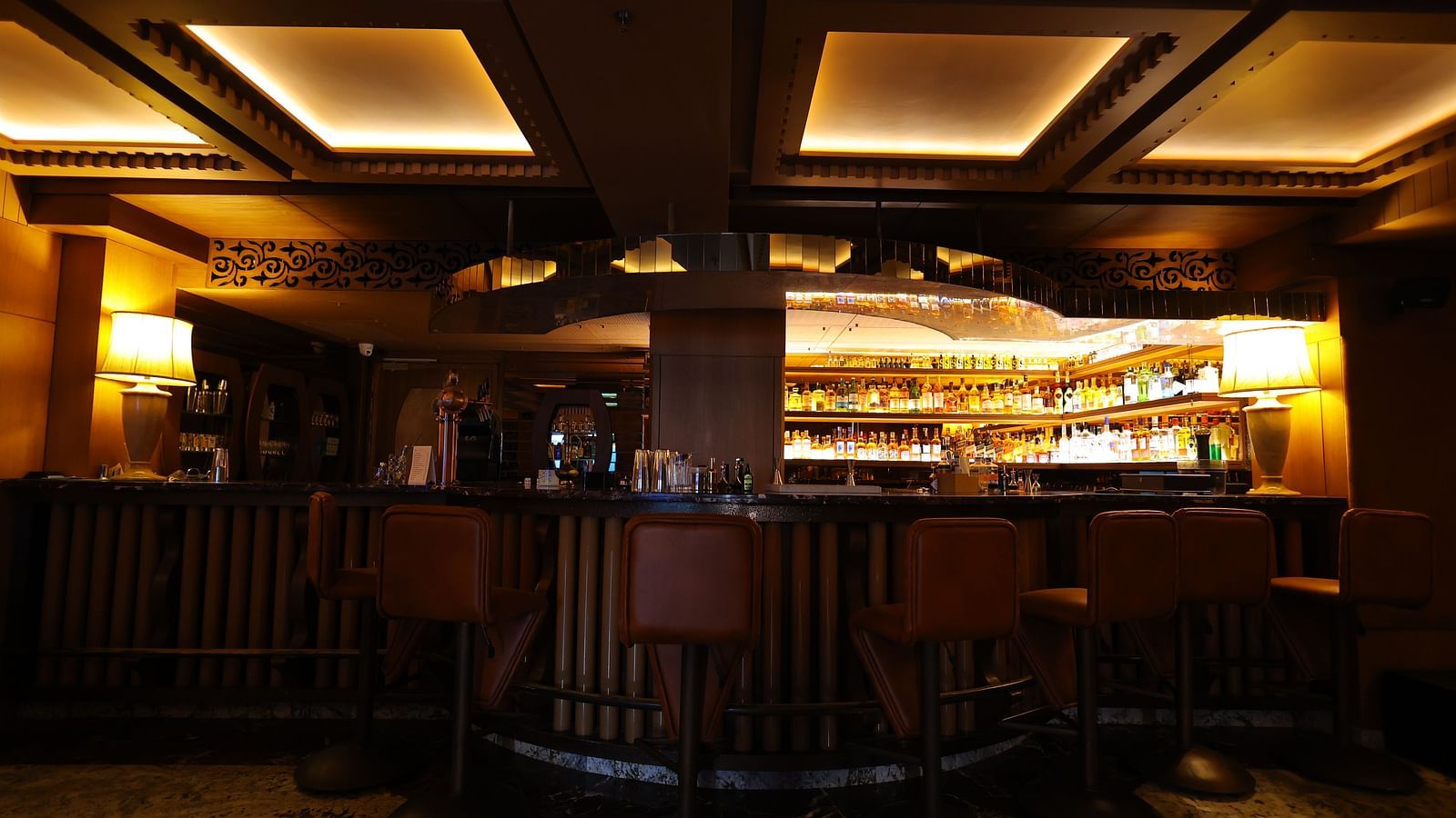 Image of bar area of JBs lounge with chairs, tables and stacked bar rack