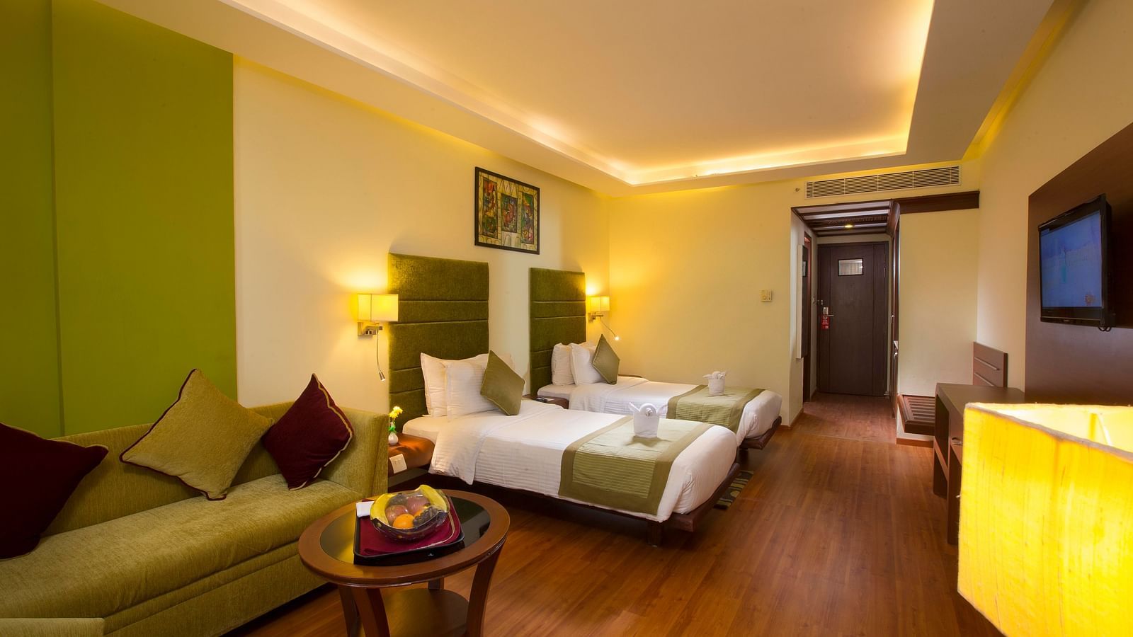 Superior Room featuring twin beds, sofa and a television at Hotel Atithi - TGI Grand, Pondicherry