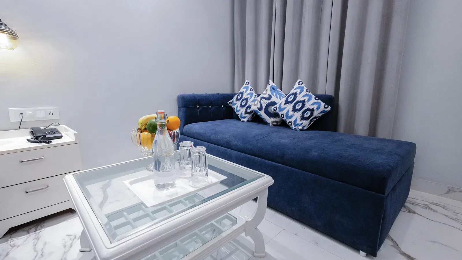 Super Deluxe Room featuring a blue chaise lounge with patterned throw pillows and a glass-topped coffee table. - Hotel Downtown17, Chandigarh