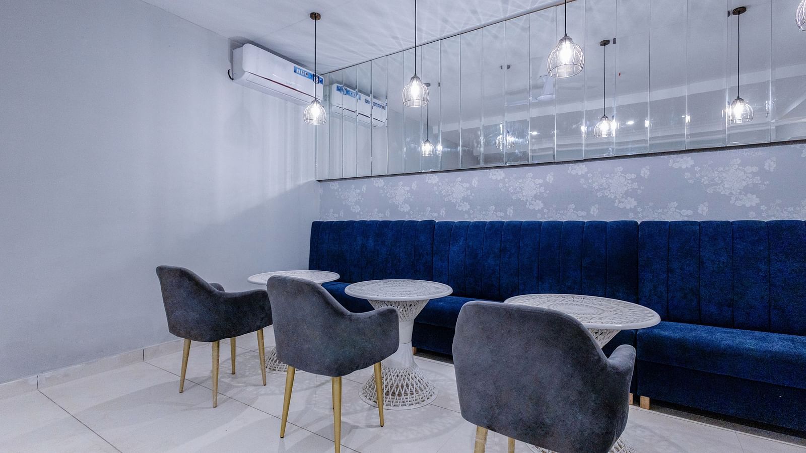 corner view shot of the restaurant with three round tables with a huge blue couch in front of it - Hotel Downtown17, Chandigarh