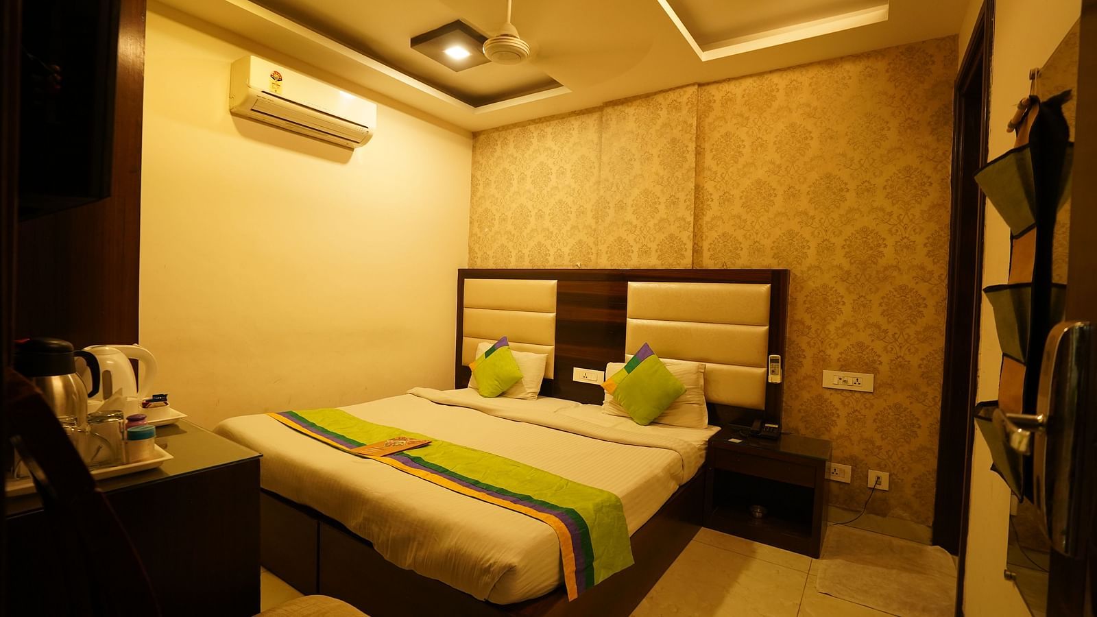 Standard Room featuring a double bed with green accents, a bedside table, and an air conditioning unit. - Hotel Dreamland, Chandigarh