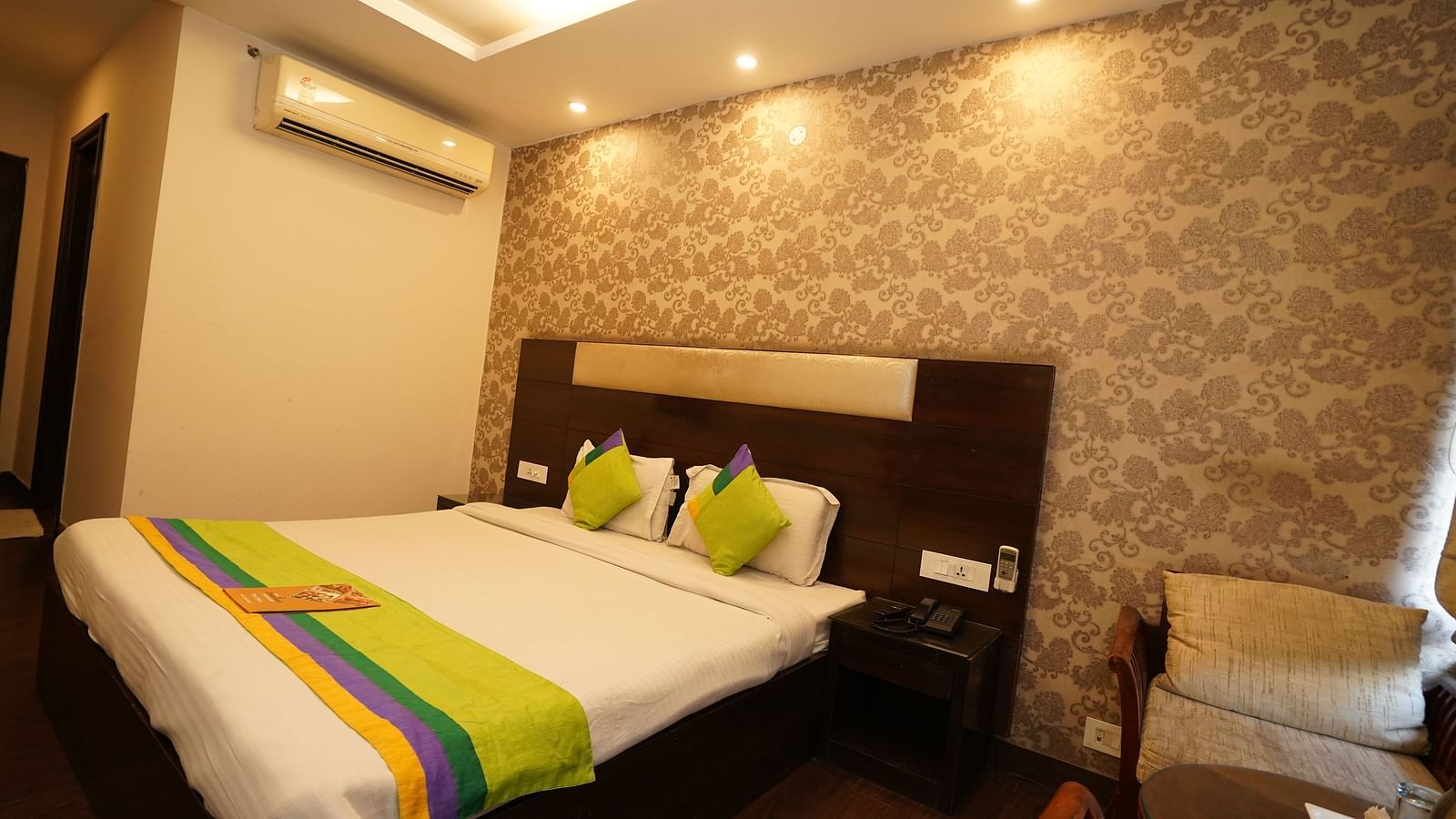 Deluxe Room featuring a king size bed with white linens and decorative green and yellow striped accents.- Hotel Dreamland, Chandigarh