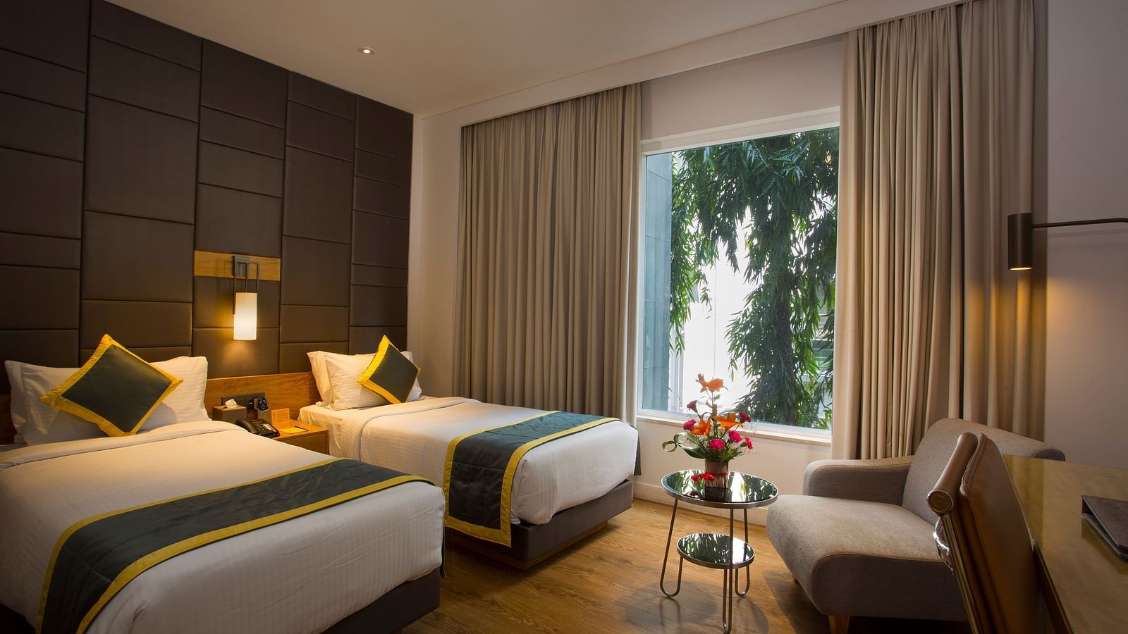a bedroom with the curtains drawn out offering views of the city with two single beds and a sofa  - Hotel Fountain Tree By TGI - JP Nagar, Bangalore