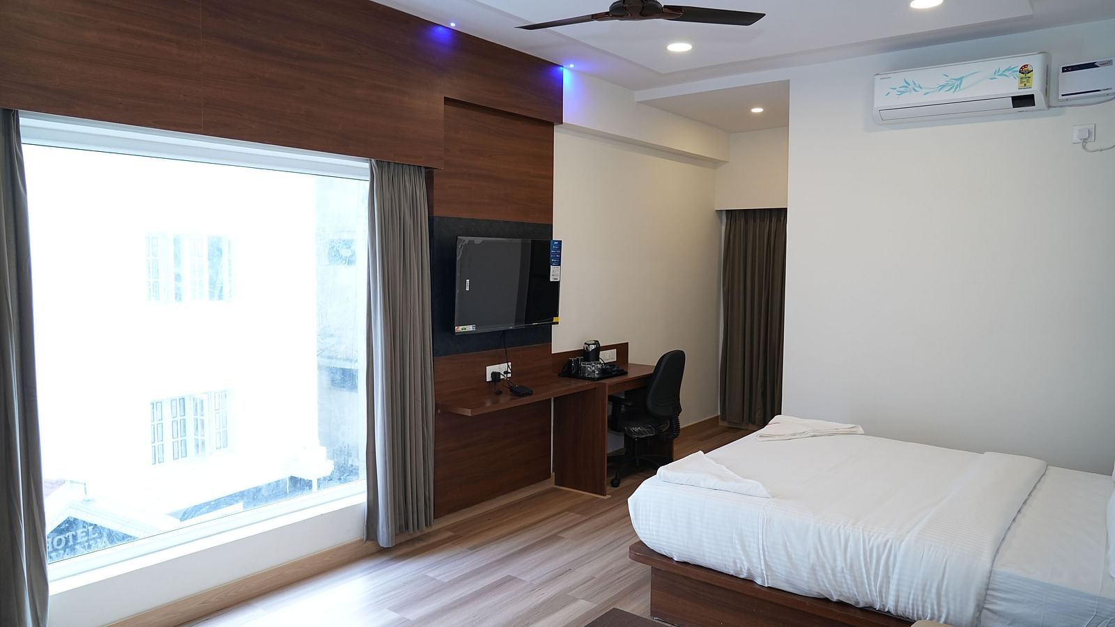 a huge window allowing plenty of natural light to enter the room highlighting the double bed and the coffee table beside it - Hotel Grand Sigma