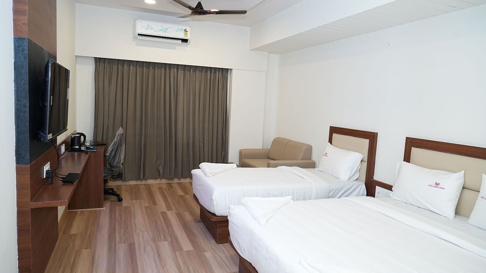 a room featuring a double bed along with a single bed along with huge windows with curtains drawn over it - Hotel Grand Sigma