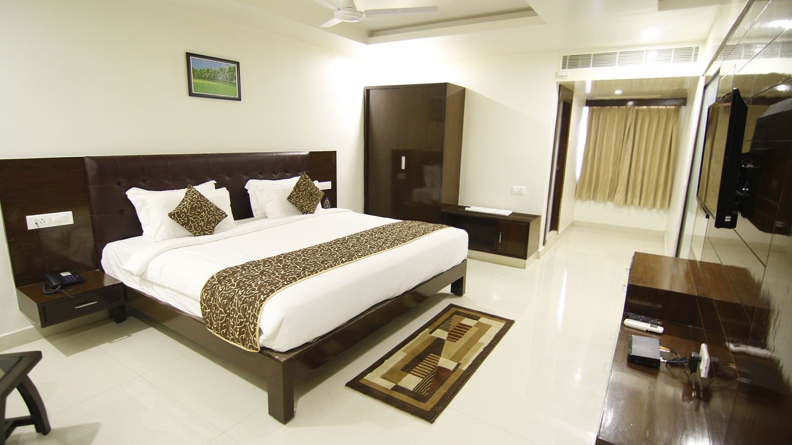 Elite Room with room with bed, wardrobe and television in front at Jyothi hall with seats arranged and lights on the ceiling at Hotel Green Apple