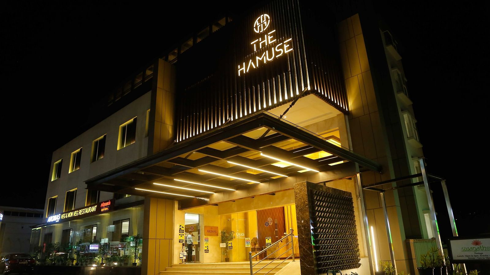 Exterior view of The Hamuse Hotel, Kodaikanal at night, brightly lit with the hotel name displayed prominently on the facade.