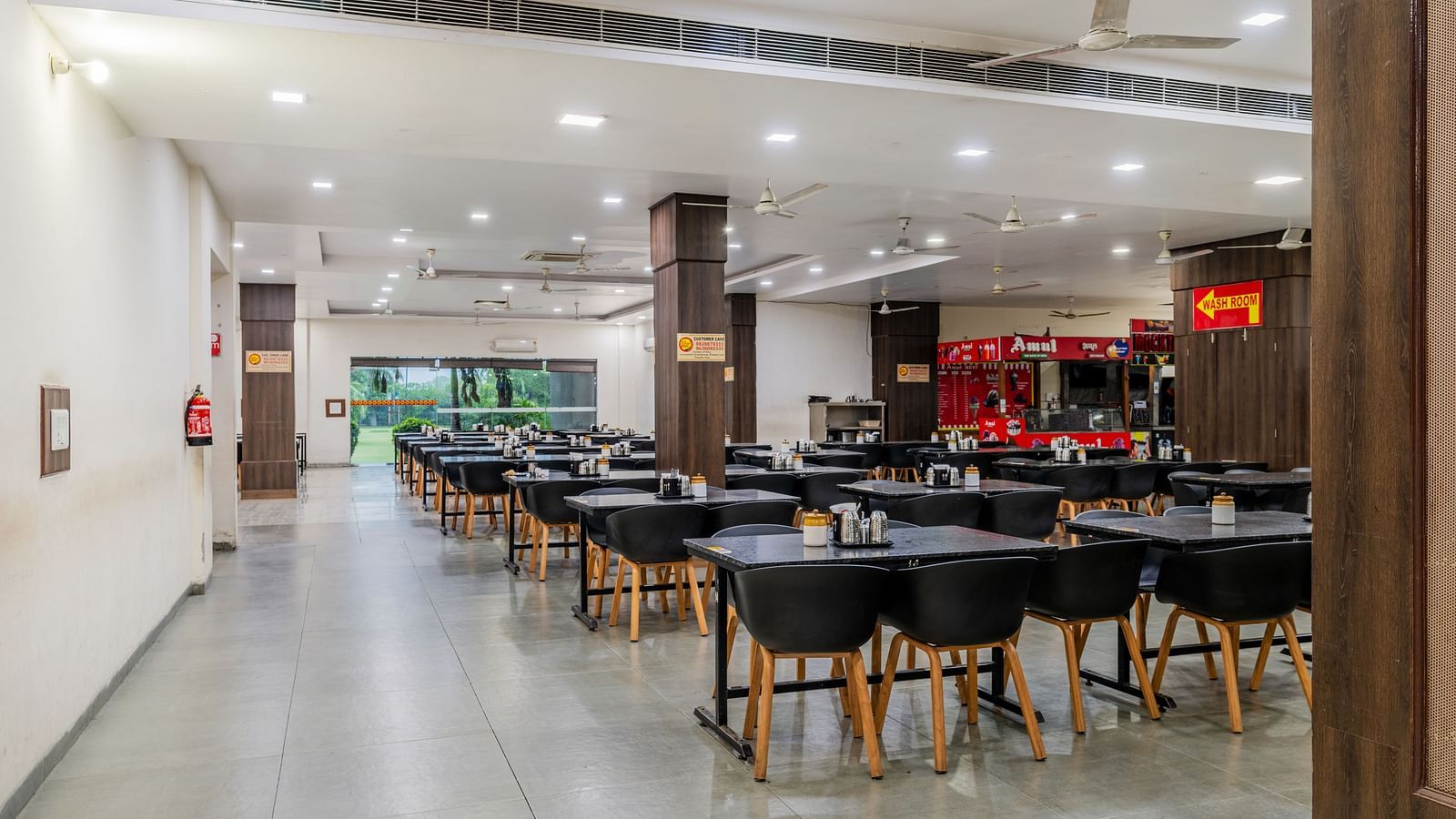 Dining tables with various seating capacities, ample lighting and eatery stalls located inside the restaurant of Hotel Highway King, Behror.