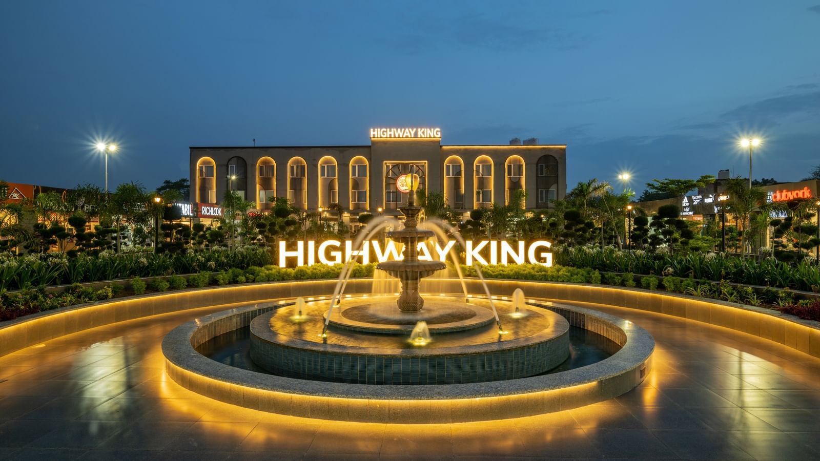 Wide shot of the facade of Hotel Highway King, Neemrana, featuring a fountain and warm lighting that highlights the view against the night sky.