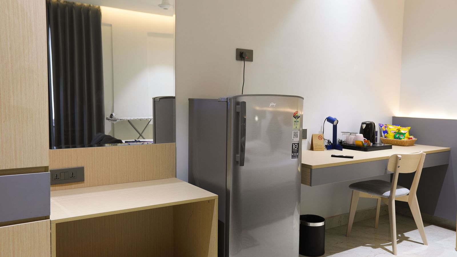 Compact work desk, mini fridge, and mirror setup inside a room at Hotel Kyzen HiTech City – Your Zenly Stay.