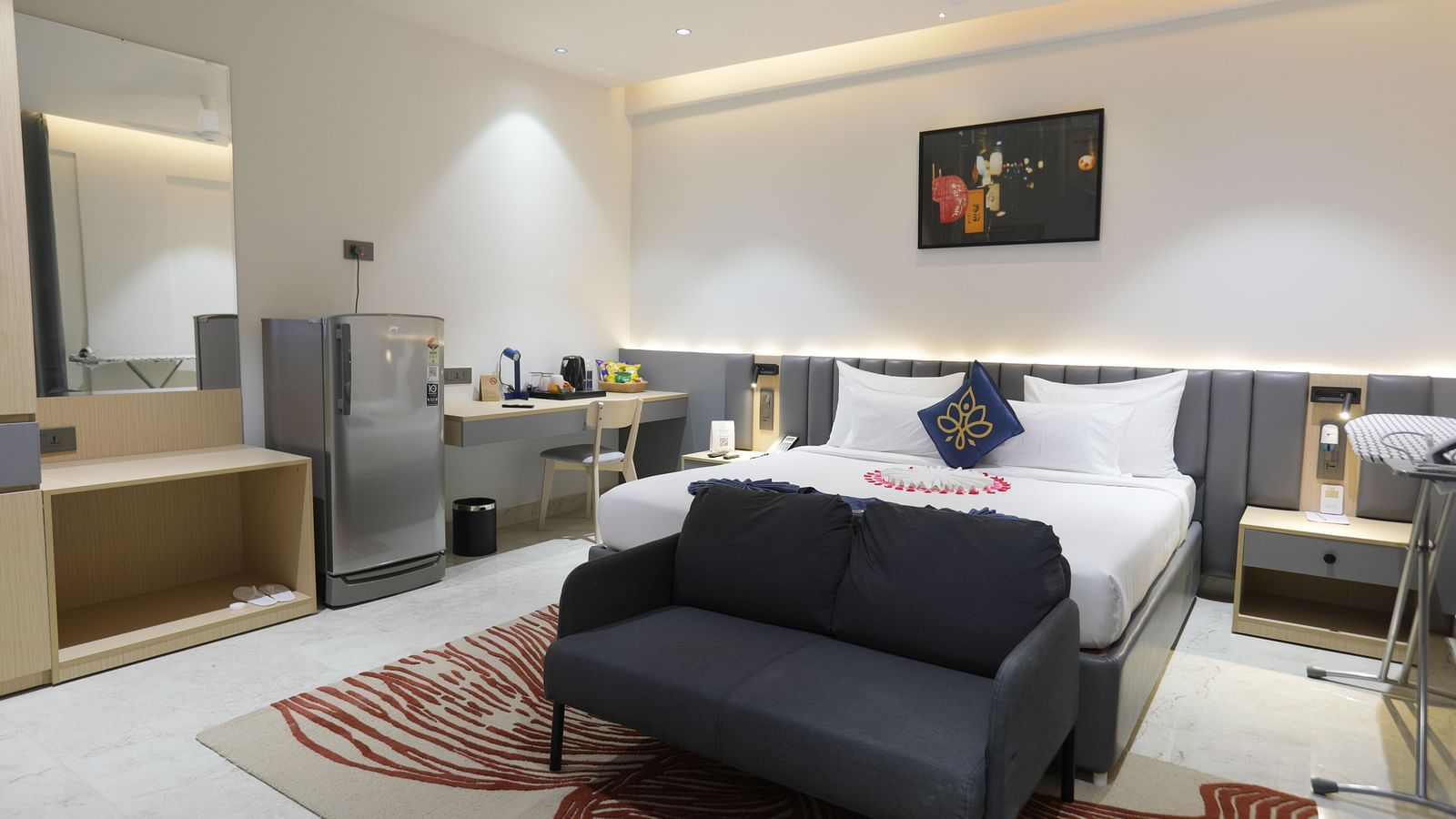A room at Hotel Kyzen HiTech City – Your Zenly Stay with a bed, couch, desk, and mini-fridge setup.