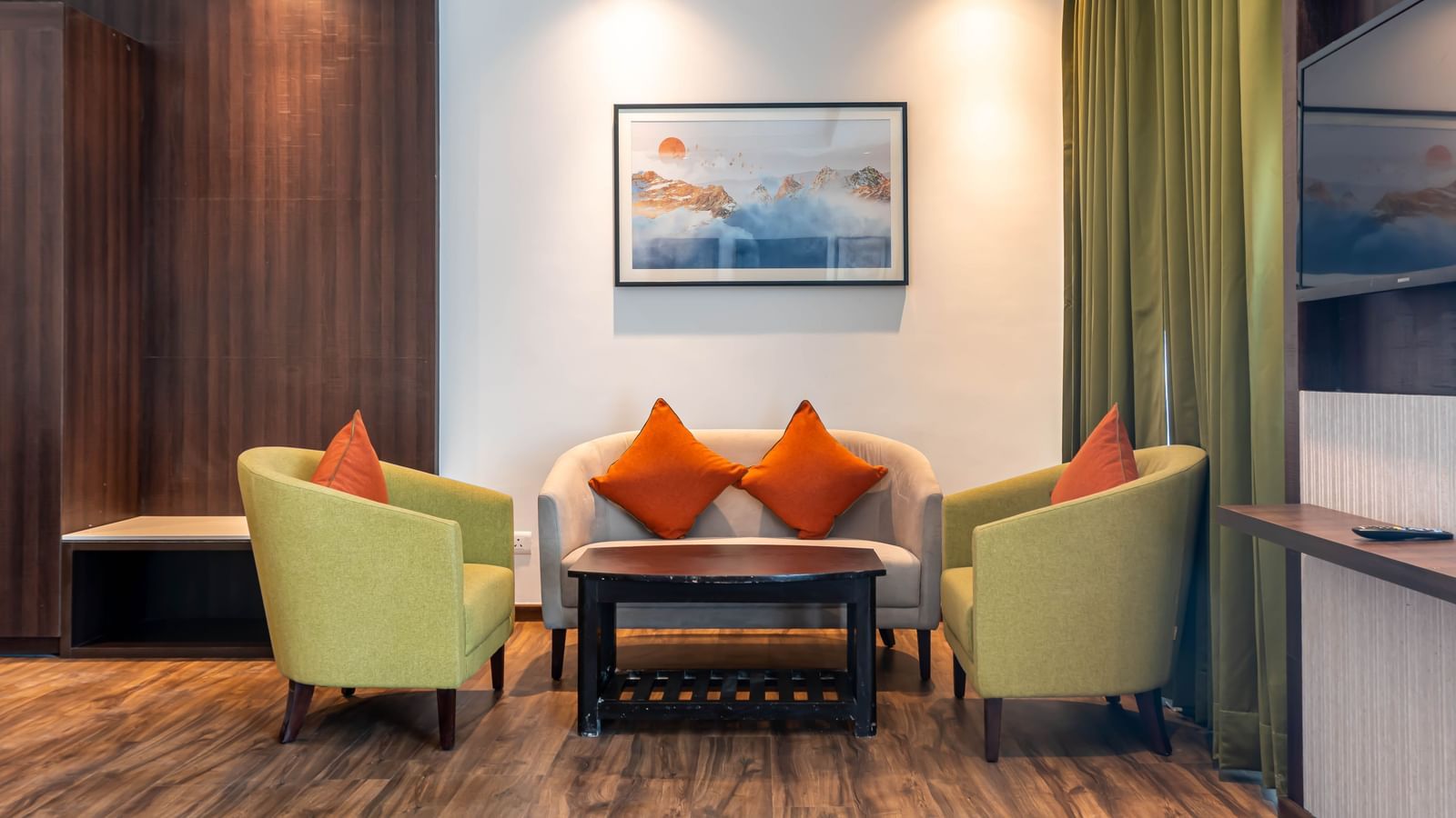 A seating area at Hotel Le ROI Lake View, Koti featuring sofa set and a centre table. On the wall there is a photo frame hanged and the room also has a flat TV sceen.