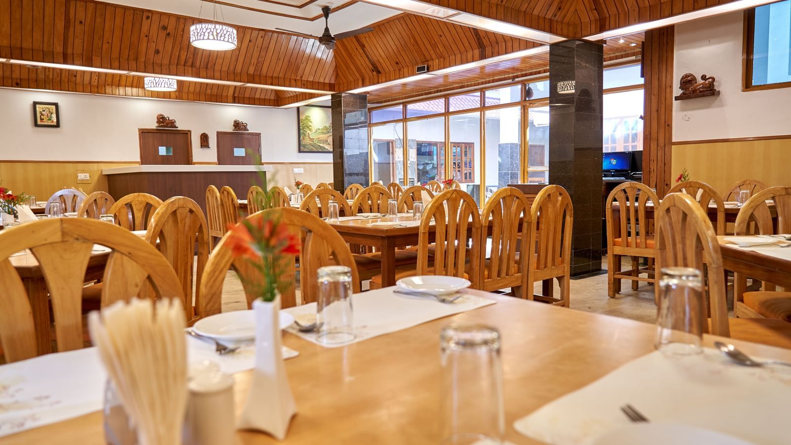 Tables elegantly set with white tablecloths and place settings in the restaurant area of Hotel Mamallaa Heritage, ready for dining.