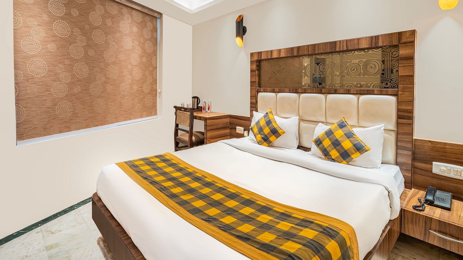 A side corner view of the bedroom at Hotel Moti Palace, featuring a comfy bed and a side table.
