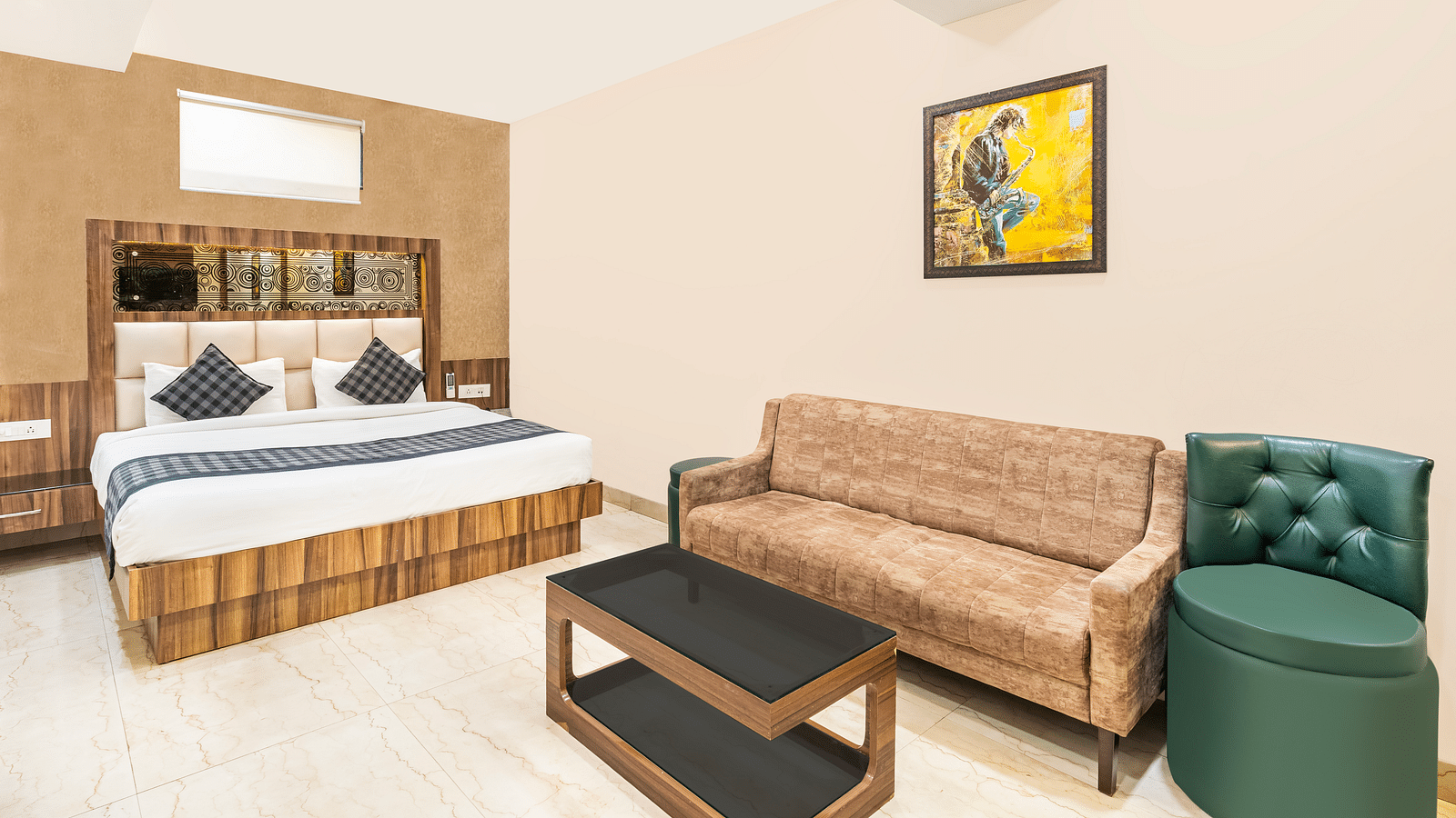 A corner view of the room at Hotel Moti Palace, showcasing a cozy bed, a comfy sofa, and a tea table.