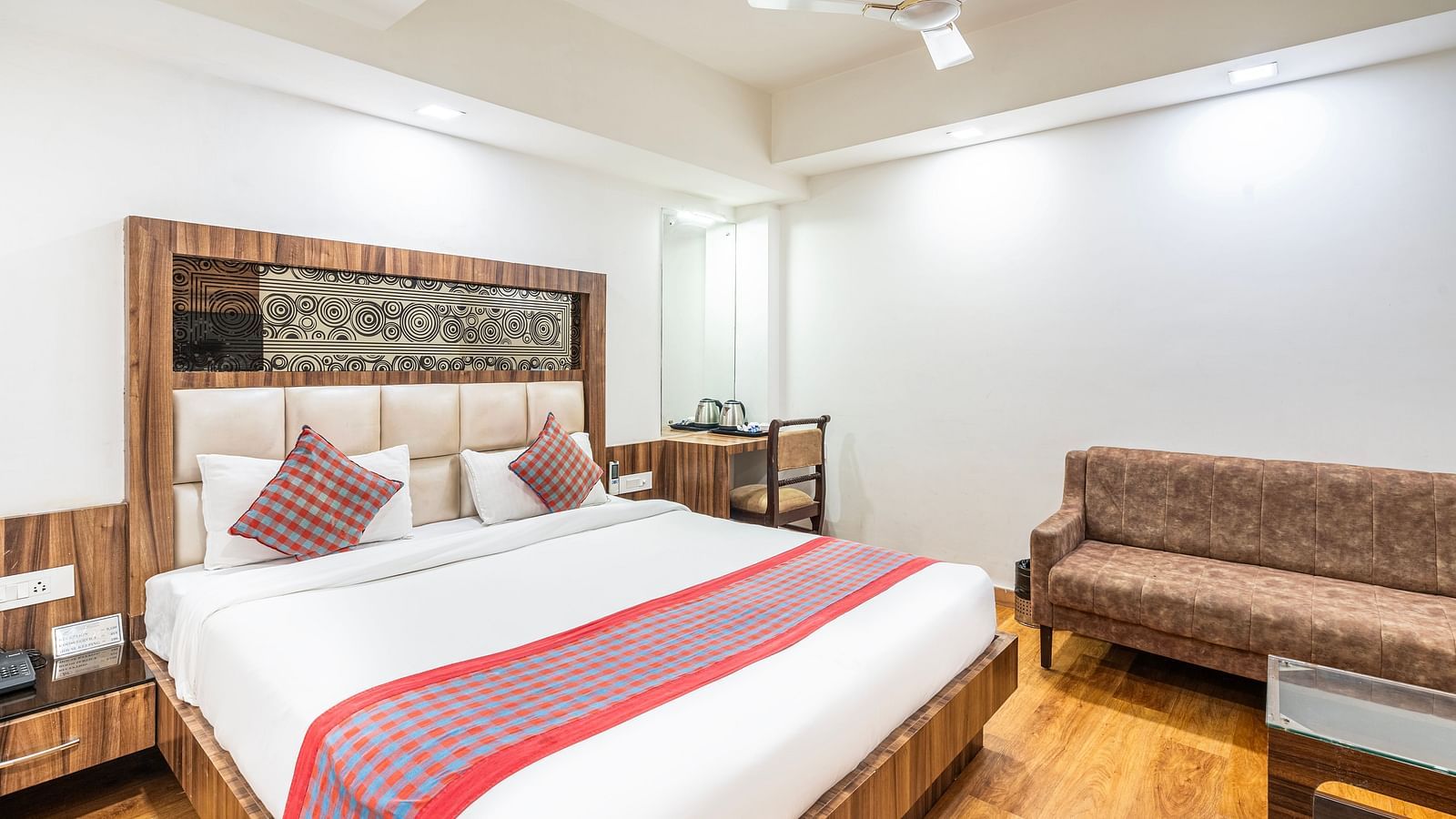A side view of the comfy bed, sofa, and tea table in a room at Hotel Moti Palace.