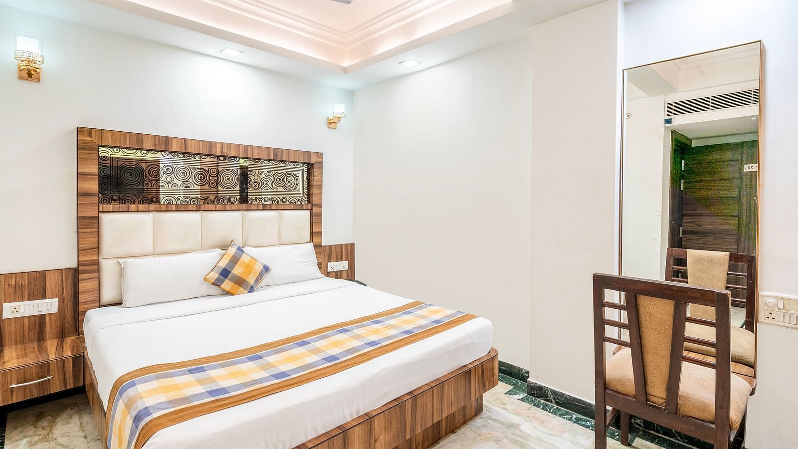 A side angle view of the bedroom at Hotel Moti Palace, featuring a comfy bed and a dressing table.