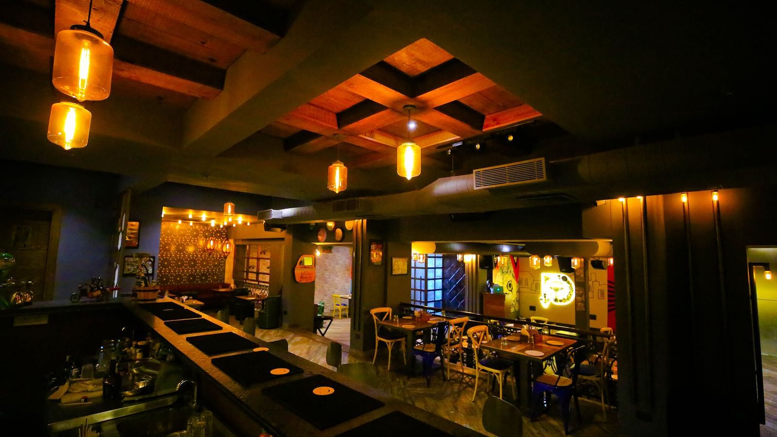A dimly-lit restaurant bar with warm pendant lighting and a cosy seating arrangement - Hotel Moti Palace