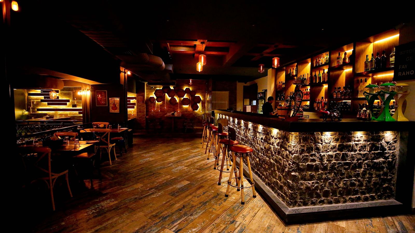 A warmly lit restaurant with a stone bar counter and wooden accents creating an inviting atmosphere - Hotel Moti Palace
