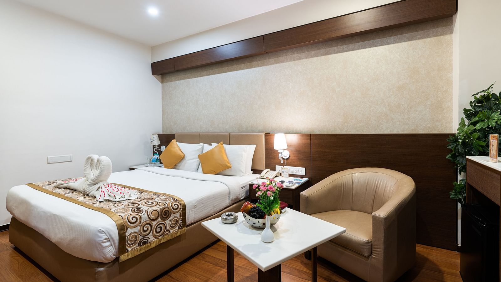 a double bed with a single seater sofa inside one of the rooms - Hotel Pai Comforts, JP Nagar