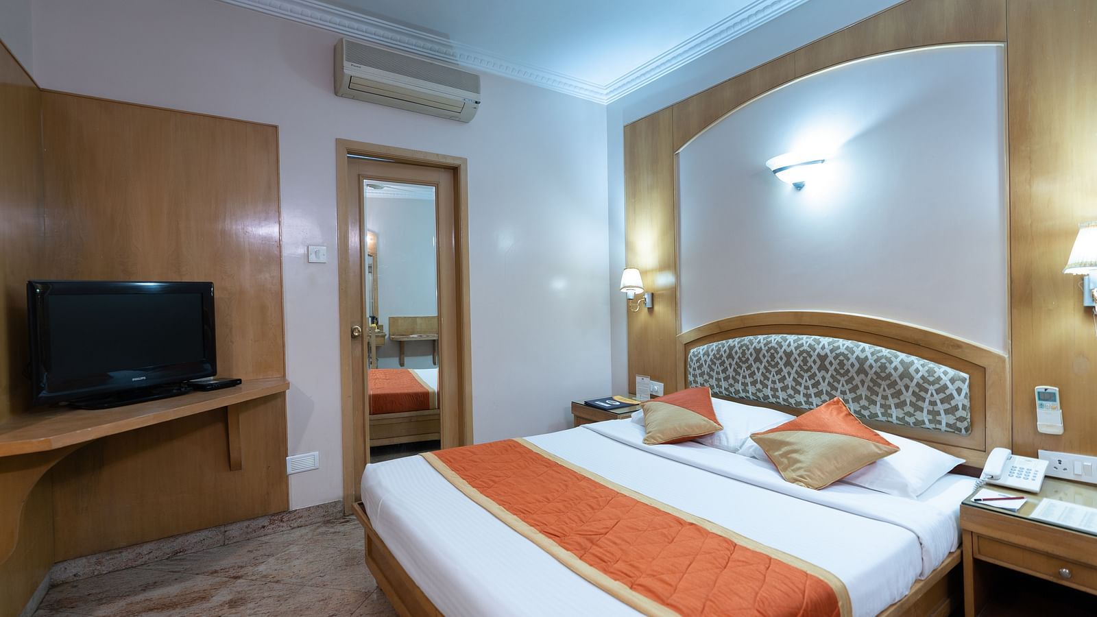 a double bed with a tv opposite it inside one of the rooms - Hotel Pai Comforts, JP Nagar